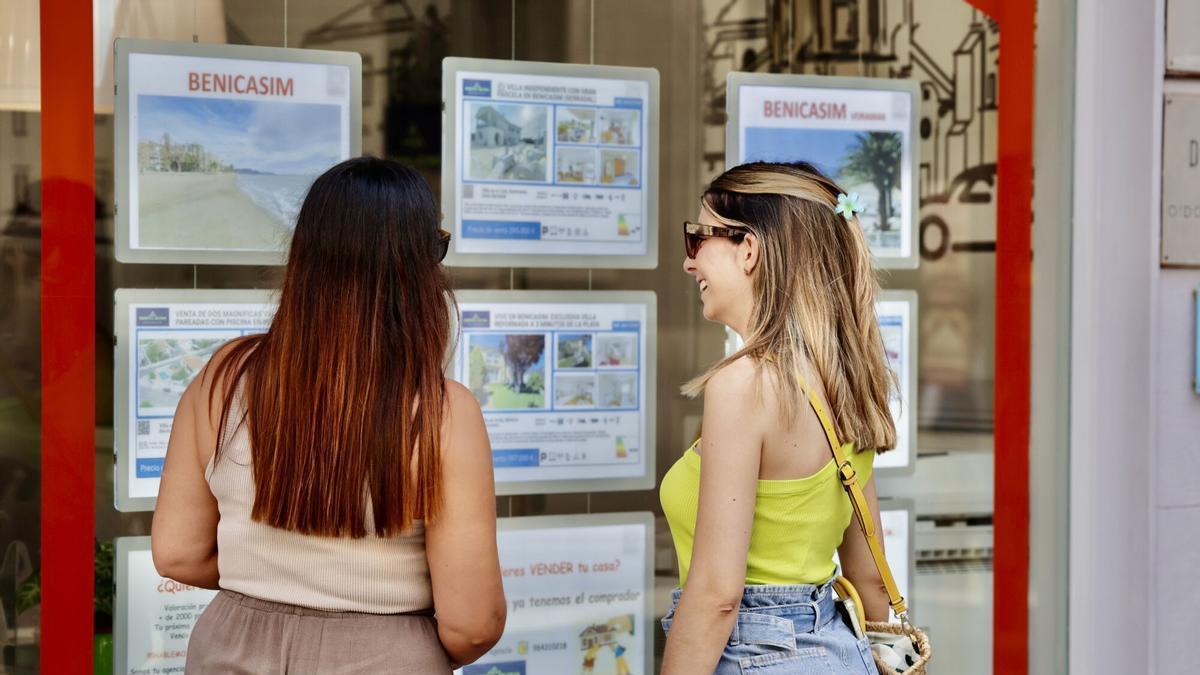 Jóvenes buscan viviendas para alquilar en una inmobiliaria.