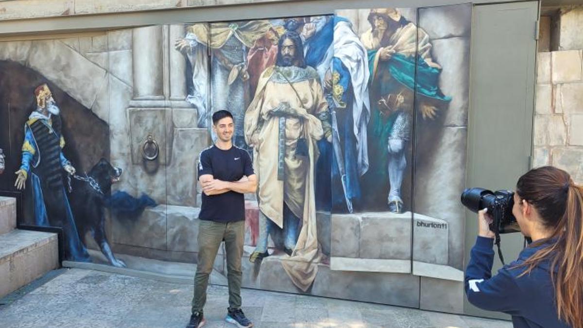 El artista urbano Edd Bhurton, este viernes junto a su pintura mural de 'La Campana de Huesca'.