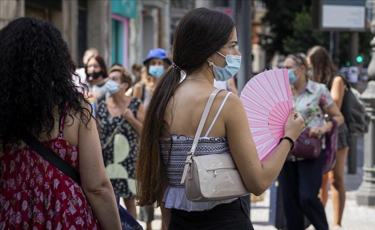 Una chica se abanica para aliviar el fuerte calor, en una calle de Valencia.