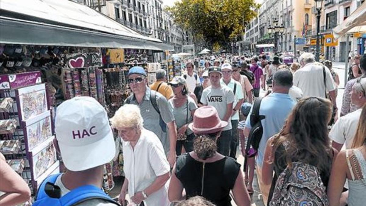 Ríos de paseantes por la Rambla, manteros, terrazas llenas, turistas con guía, y oferta de fruta, bebidas y suvenires en los quioscos volcados en el visitante.