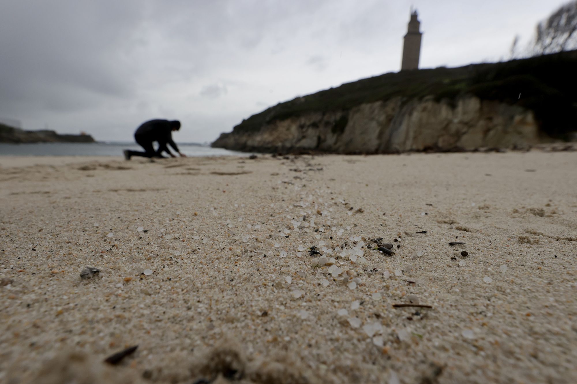 Una persona recoge pellets en la playa de As Lapas en A Coruña