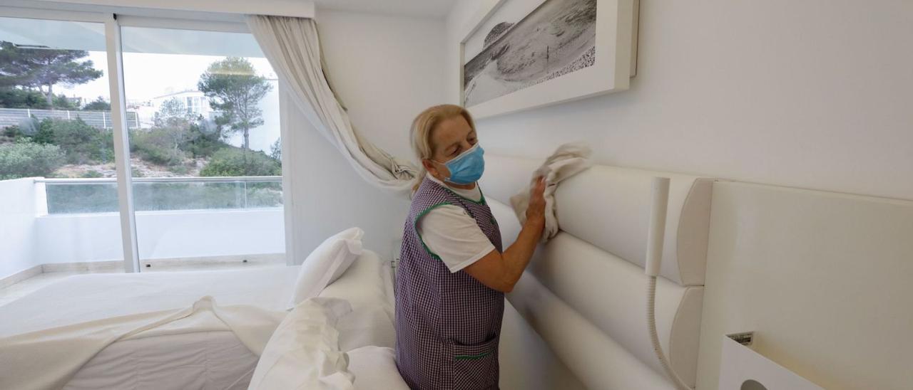 Una camarera de piso retira una cama para limpiar una habitación de hotel. | J.A.RIERA