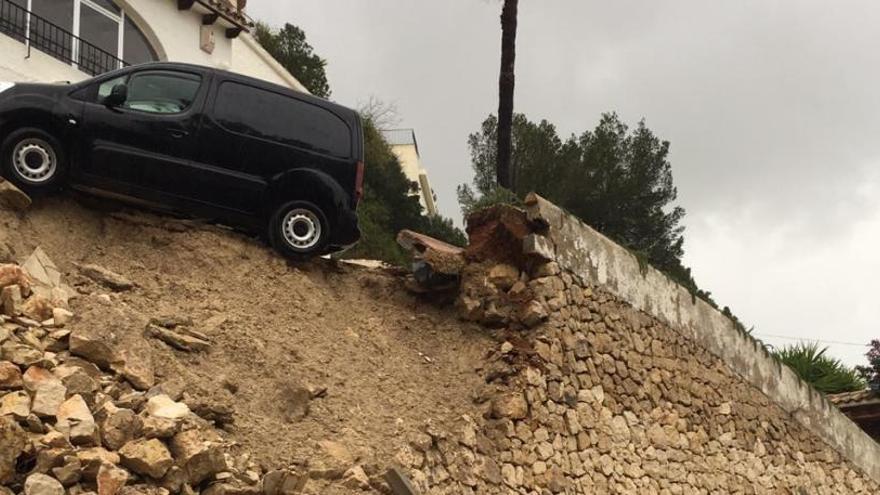Una grúa rescata un coche a punto de caer tras el derrumbe de un muro en Moraira