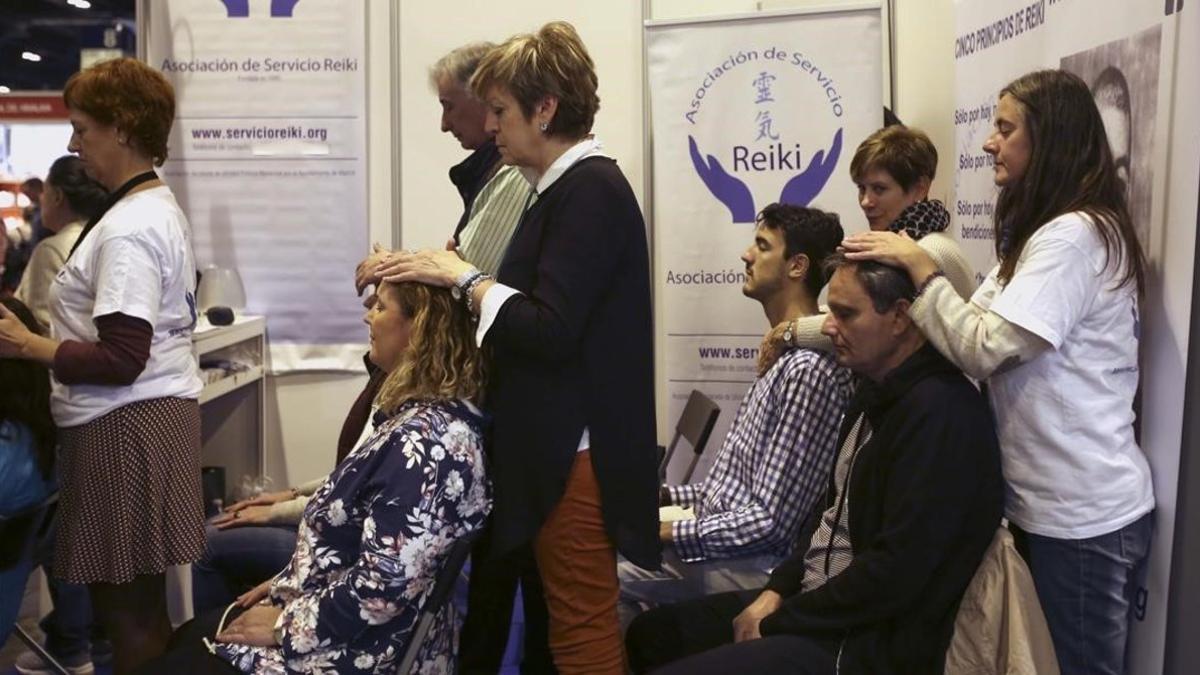 Un grupo de personas se somenten a una sesión de Reiki, considerada una pseudoterapia, en el parque ferial de Madrid.