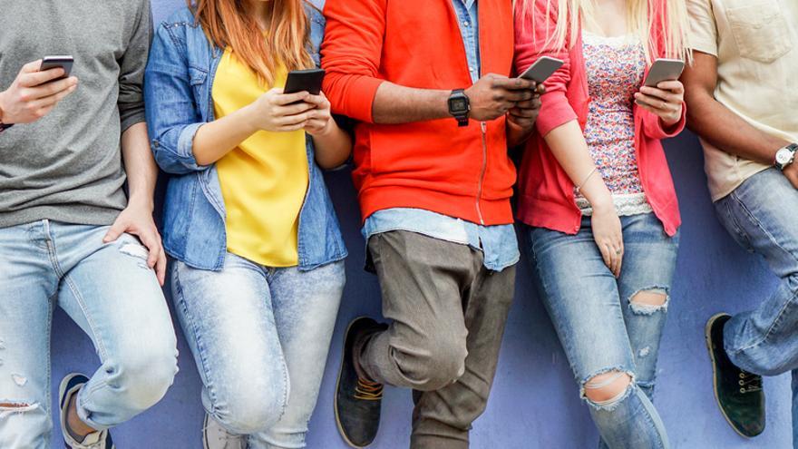 Un grupo de jóvenes consulta su teléfono móvil.