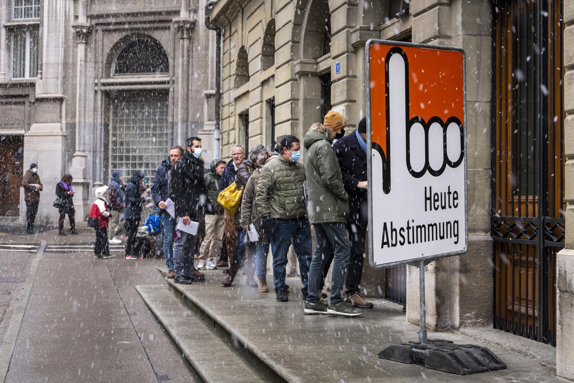 Un grupo de ciudadanos suizos hace cola para votar en el referéndum en Fribourg