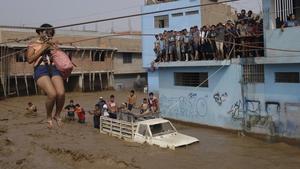 Una mujer es evacuada en una calle inundada por las lluvias en Lima.