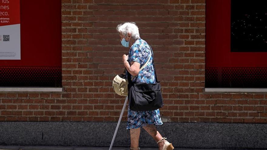 Una anciana con mascarilla camina por la calle.