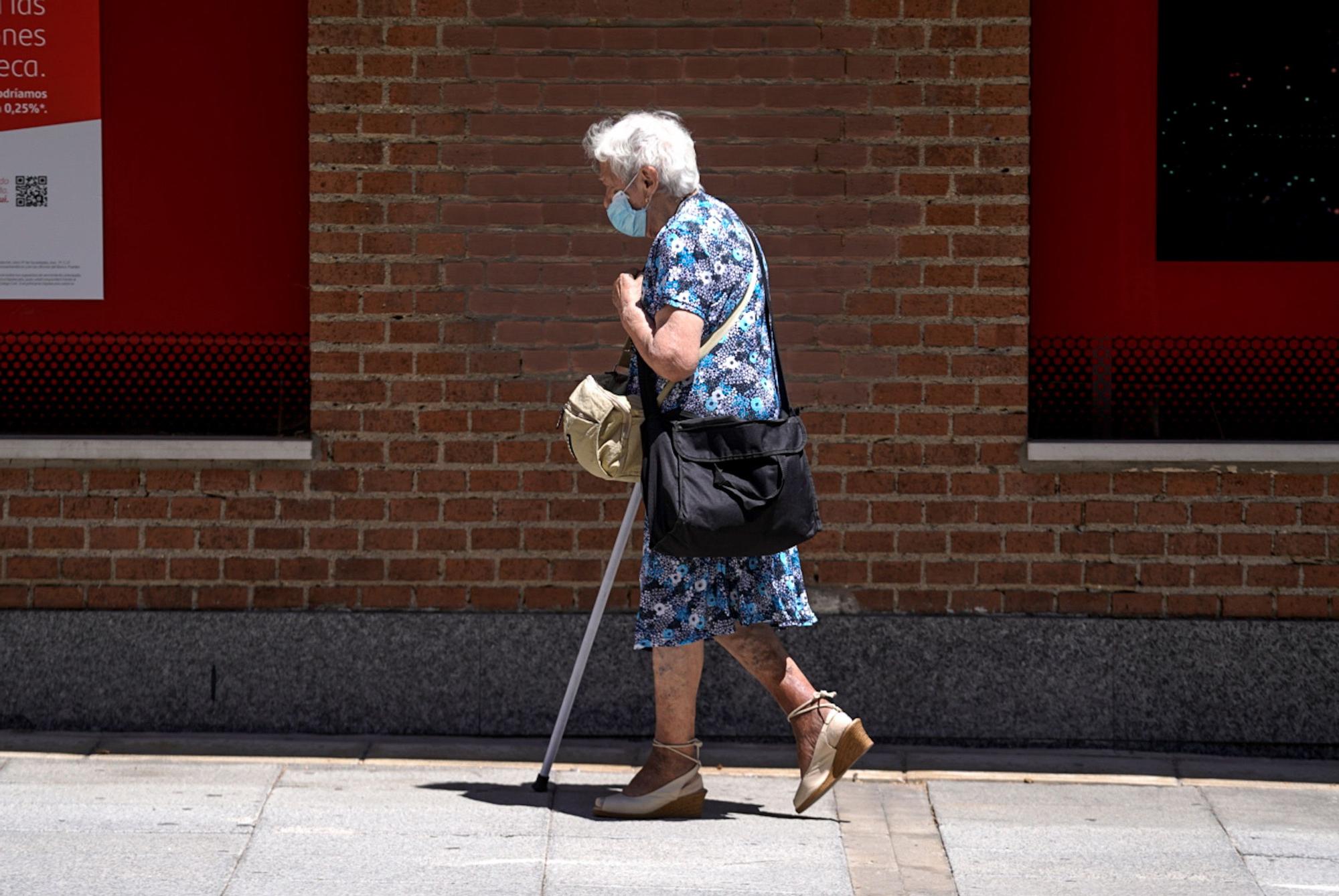 Archivo - Una anciana con mascarilla camina por la calle