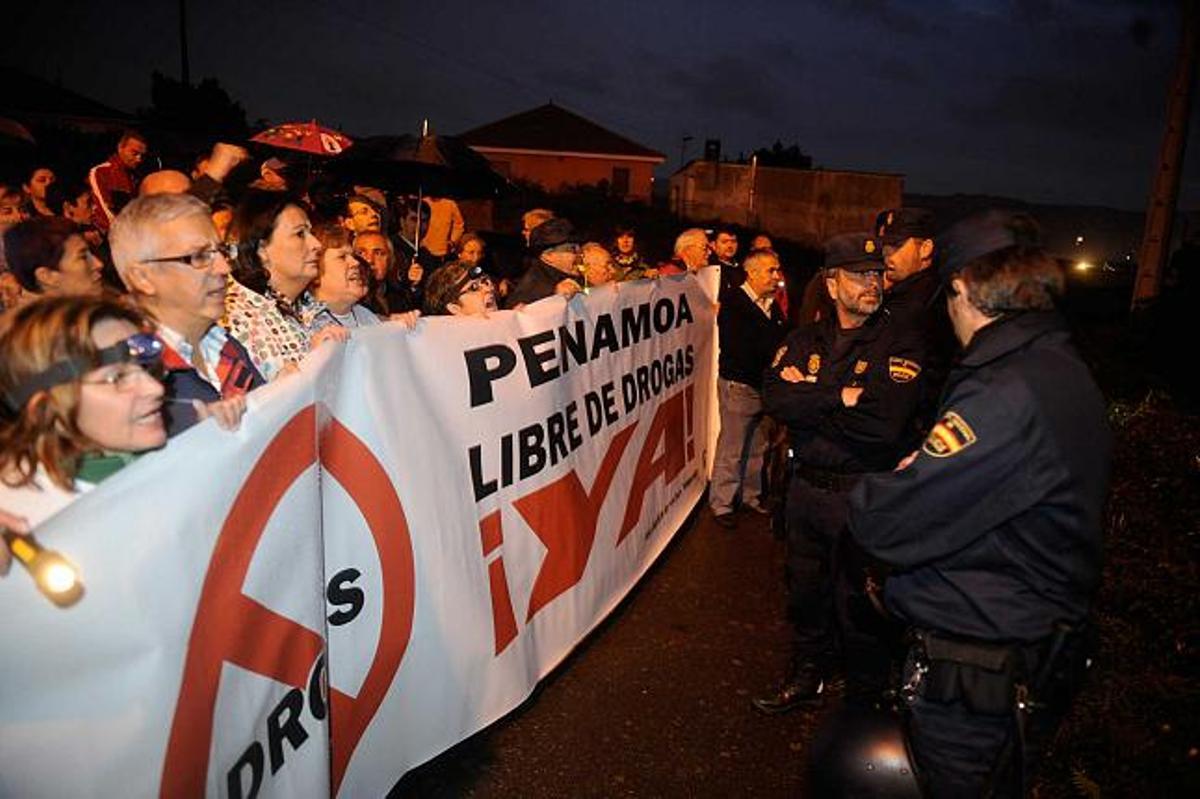 Manifestantes y policías, ayer, a la entrada del asentamiento chabolista de Penamoa. / juan varela