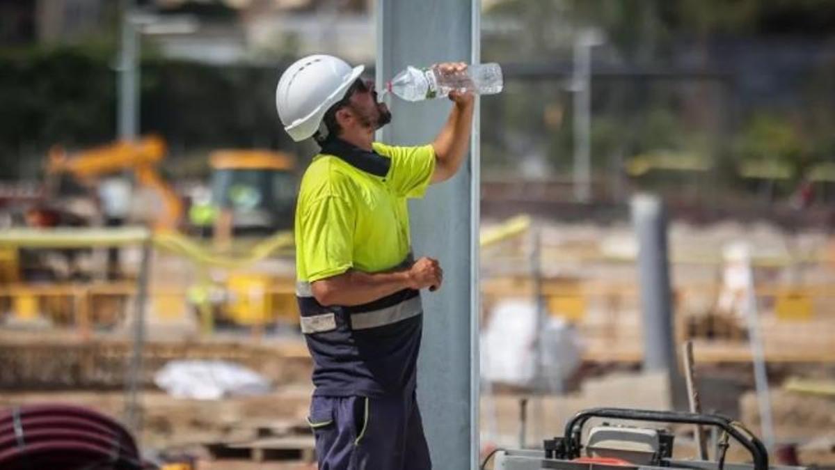 Un trabajador de la construcción bebe agua para hidratarse.