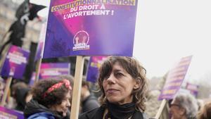 Una mujer muestra un cartel reclamando la inclusión en la Constitución del derecho al aborto, durante la manifestación del pasado 8 de marzo en París.