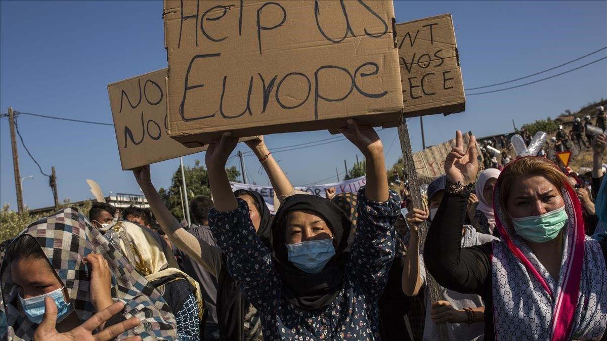 Una mujer refugiada de Moria muestra en una protesta un cartón en el que hay escrito en inglés Europa ayúdanos.