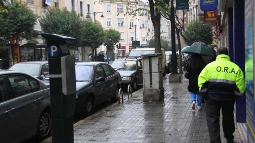 Un controlador de la ORA pasa junto a un expendedor de tickets por la calle Alzamora.