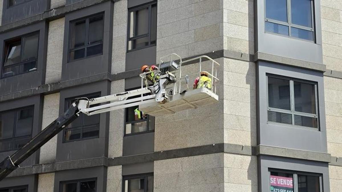 Operarios trabajando en la fachada del edificio en la confluencia entre Aragón y Bailén.