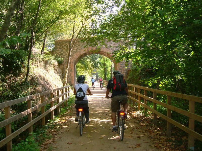 De Olot a Girona en bicicleta | La Ruta del Carrilet es una vía exclusiva para transeúntes y ciclistas que aprovecha el recorrido del antiguo tren de vía estrecha –carrilet– que enlazaba Olot con Girona. Este modesto ferrocarril surcaba las orillas de los ríos Ter, Bruguent y Fluvià bajo la inquietante sombra de los volcanes de La Garrotxa. La senda rehabilitada en 1997 se extiende a lo largo de 39,7 kilómetros. Permite conocer las comarcas de Gironès y Baix Empordà. Atraviesa núcleos de interés como Castell d´Aro, con un casco antiguo medieval. Los terrenos fueron cedidos por Ferrocarriles Españoles de Vía Estrecha (FEVE) y con los años el proyecto se fue ampliando hasta permitir bajar desde el alto Pirineo hasta el Mediterráneo a lo largo de casi 135 kilómetros de vías verdes.