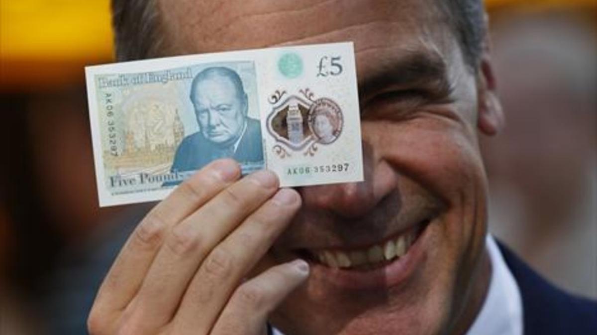El gobernador del Banco de Inglaterra muestra el billete.