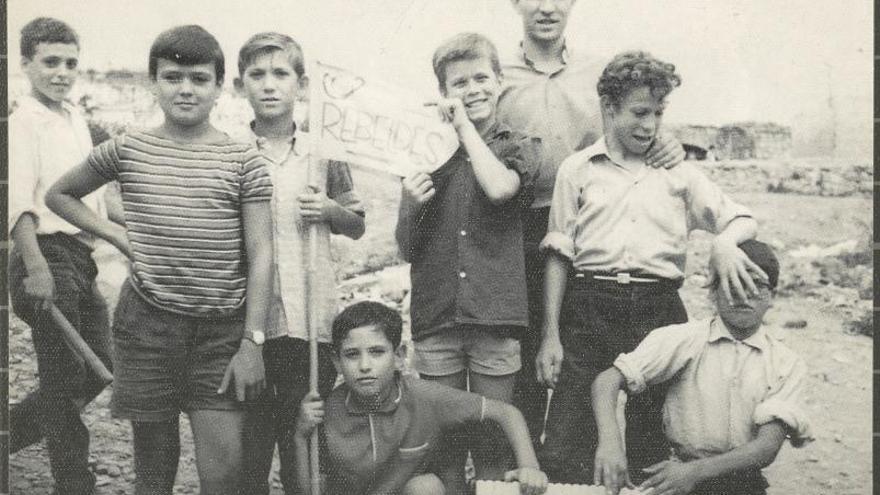 2 Retrat d’un grup de nens residents a les barraques del castell de Montjuïc amb una bandera on es llegeix: «Rebeldes»; al fons, el castell de Montjuïc, l’any 1963. F  | AJUNTAMENT DE GIRONA/CRDI 