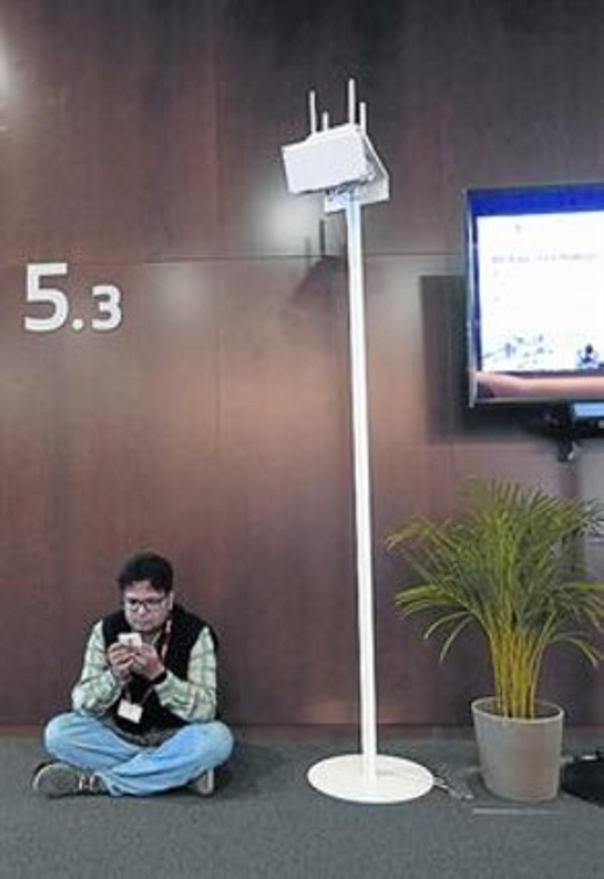 Un asistente del MWC, junto a una antena. Un asistente del MWC, junto a una antena.