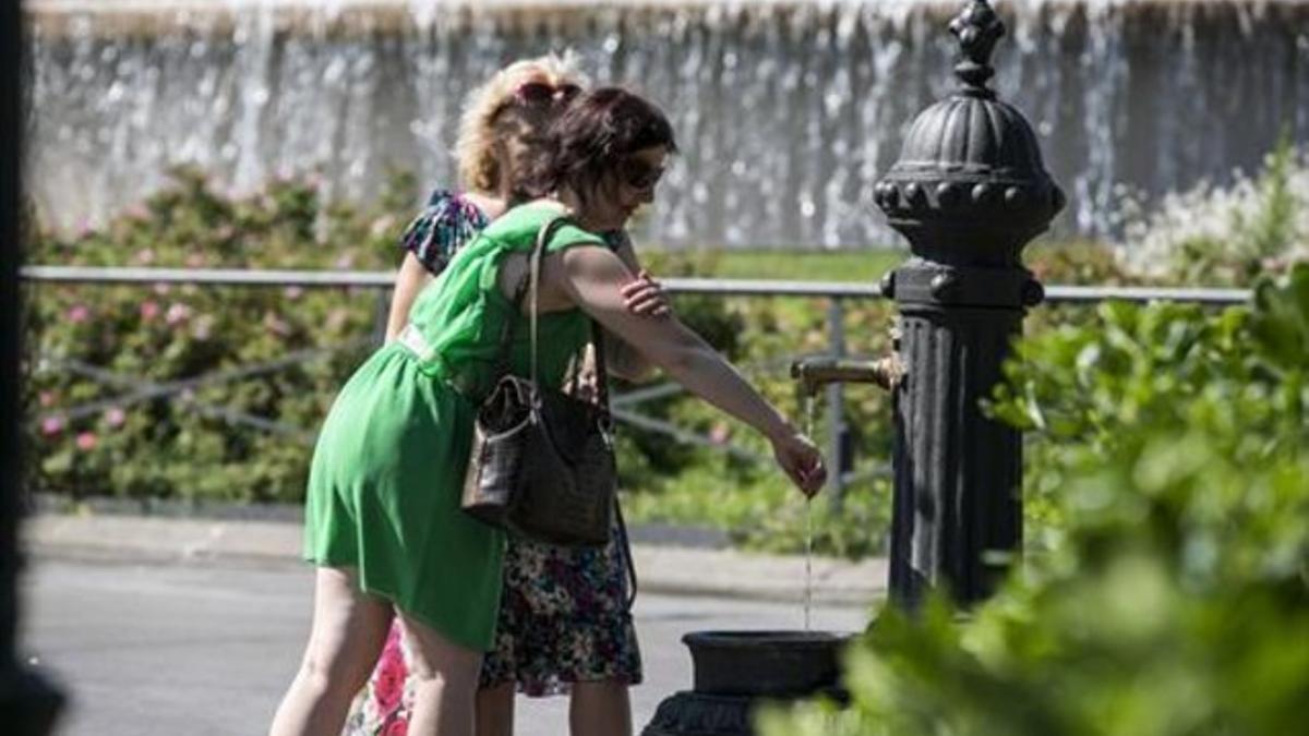 Dos mujeres en una fuente de la plaza de Catalunya de Barcelona, ayer.