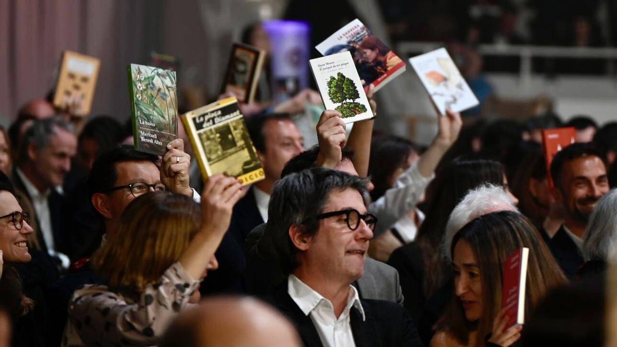 El público muestra los libros que han traído a la 75 Nit de les Lletres Catalanes que se celebra en el Palau Nacional