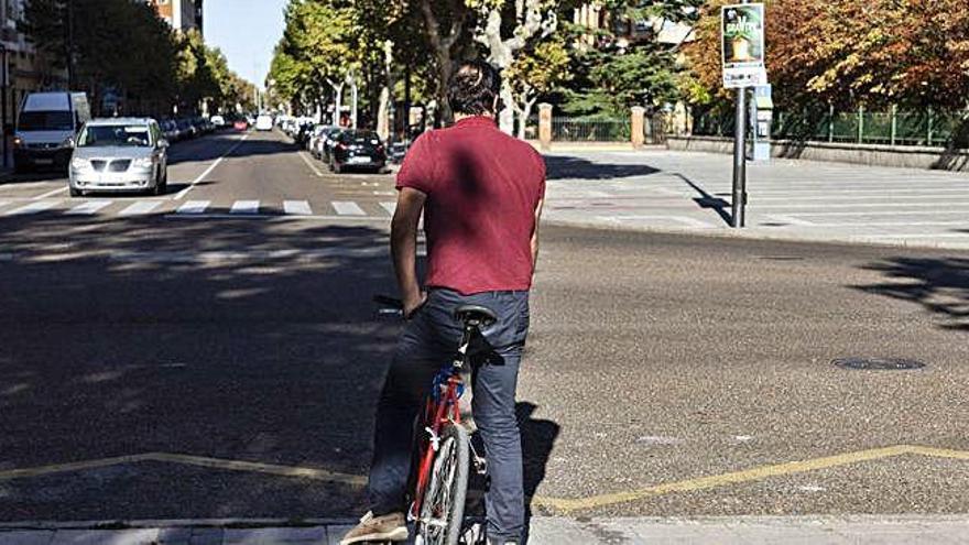 Un ciclista aguarda en La Marina antes de emprender la marcha hacia la avenida de Requejo.