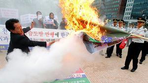 Un policia sud-coreà dispara un extintor contra un manifestant que encén un cartell amb la cara del líder nord-coreà Kim Jong-il.
