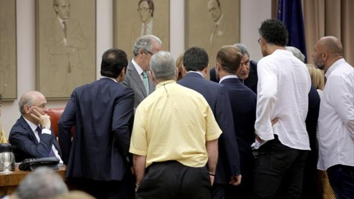 Los portavoces de los grupos hablan con el presidente de la comisión, ante la mirada del ministro, ayer en el Congreso.