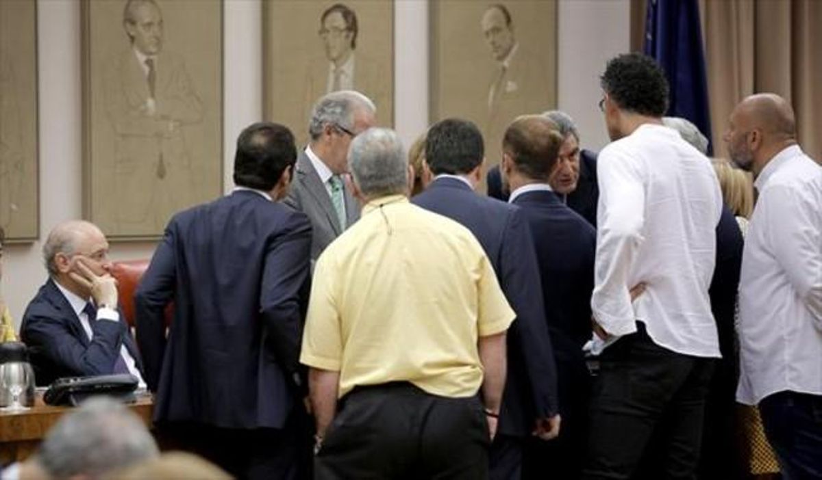 Els portaveus dels grups parlen amb el president de la comissió, davant la mirada del ministre, ahir al Congrés.