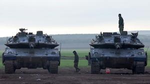 Un soldado israelí camina entre dos tanques de batalla israelíes desplegados a lo largo de la frontera con la Franja de Gaza