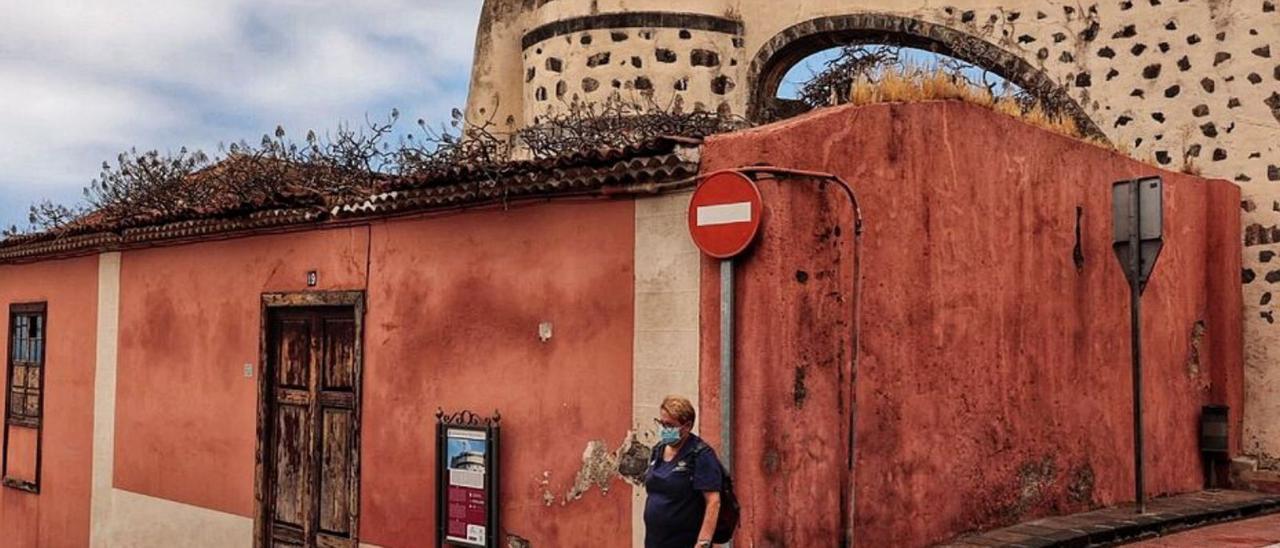 Una mujer camina por una calle de la Villa Arriba, junto a un antiguo molino