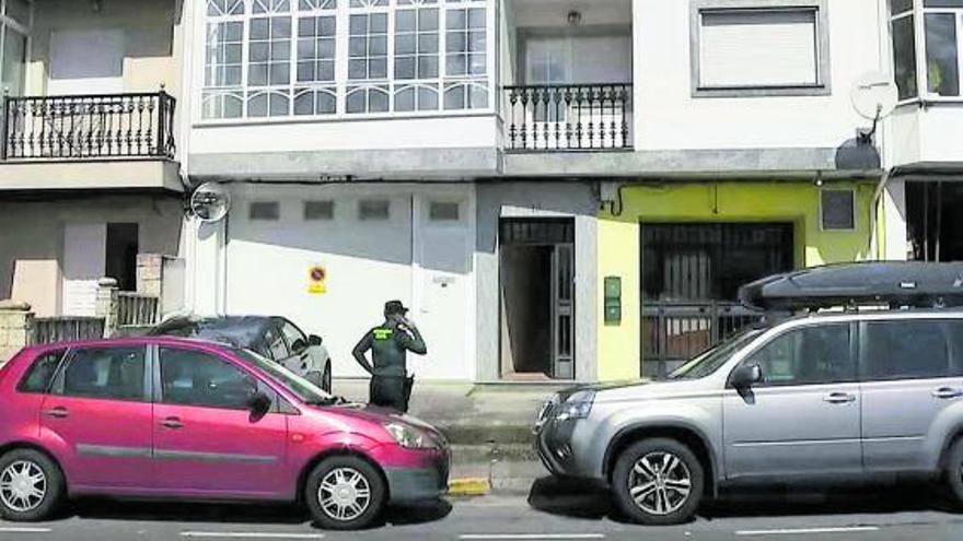 Un axente da Garda Civil diante do portal do edificio de Esteiro onde se produciu o suceso. |   // TVG