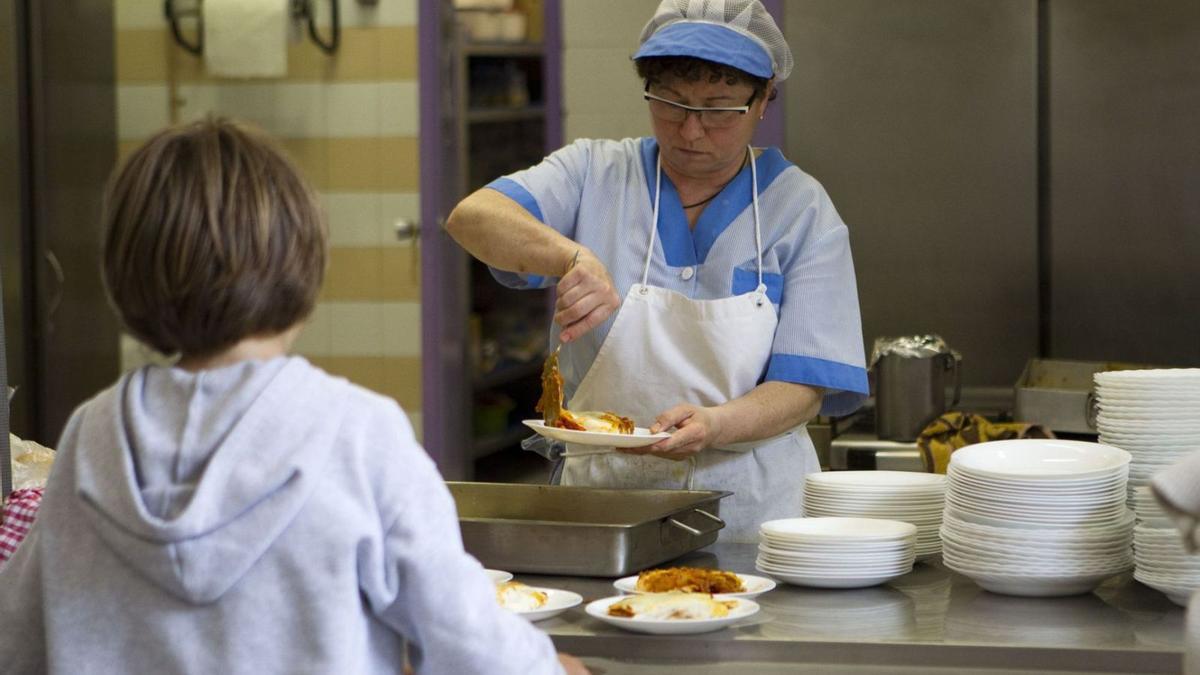 Una cocinera sirve la comida a un alumno en un colegio, en una imagen de archivo. | EL PERIÓDICO