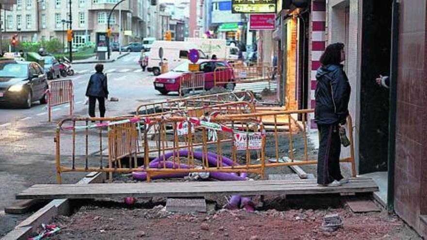 Una vecina accediendo a un portal afectado por las obras de reforma de la calle Alfonso Camín.