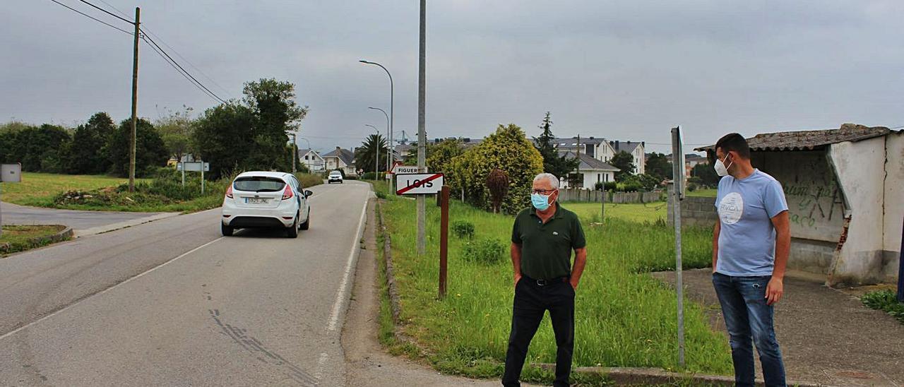 Francisco Martínez e Iván García, en la entrada a la localidad de Figueras, donde piden una acera y un apeadero para el autobús. | T. Cascudo