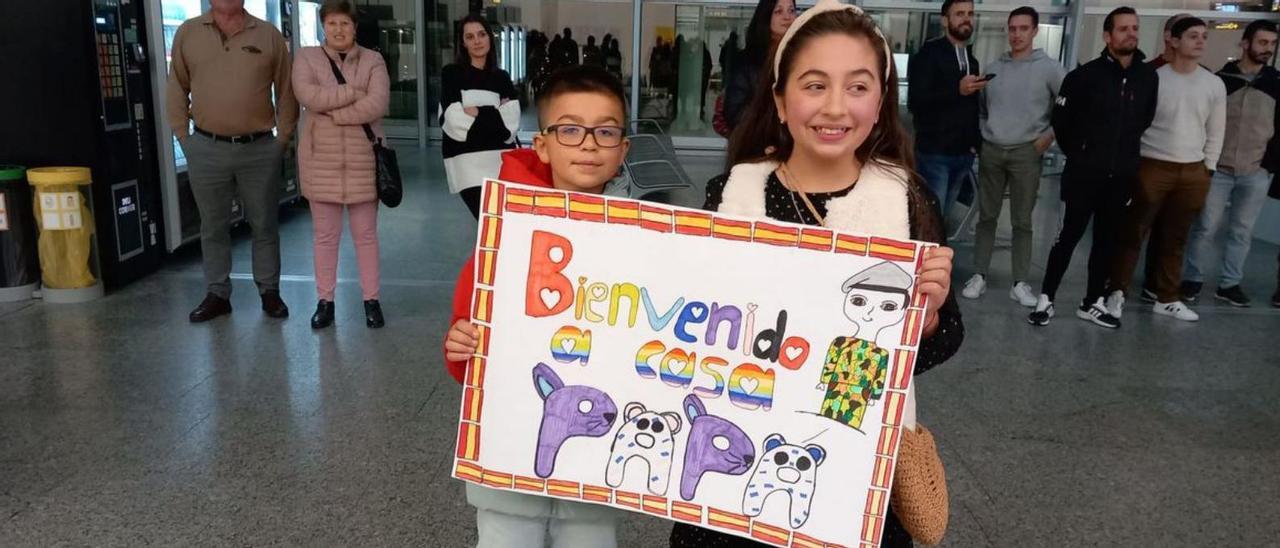 Dos niños muestran un cartel de bienvenida.
