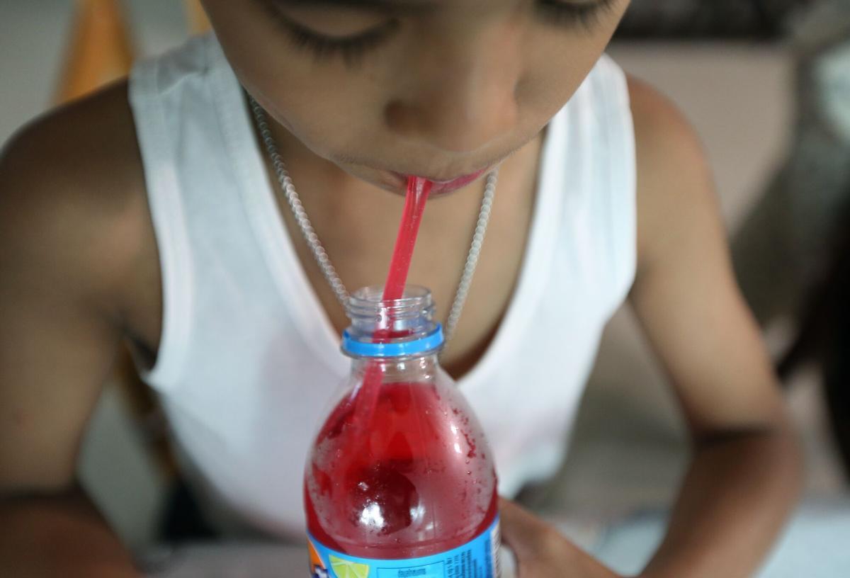 Un niño se bebe un refresco de fresa con una pajita, el verano pasado.