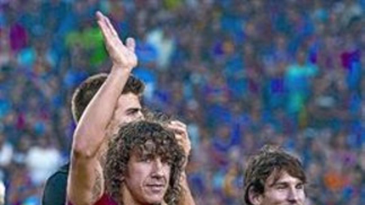 Puyol, con la camiseta de apoyo a Roqué, y Messi, el domingo.