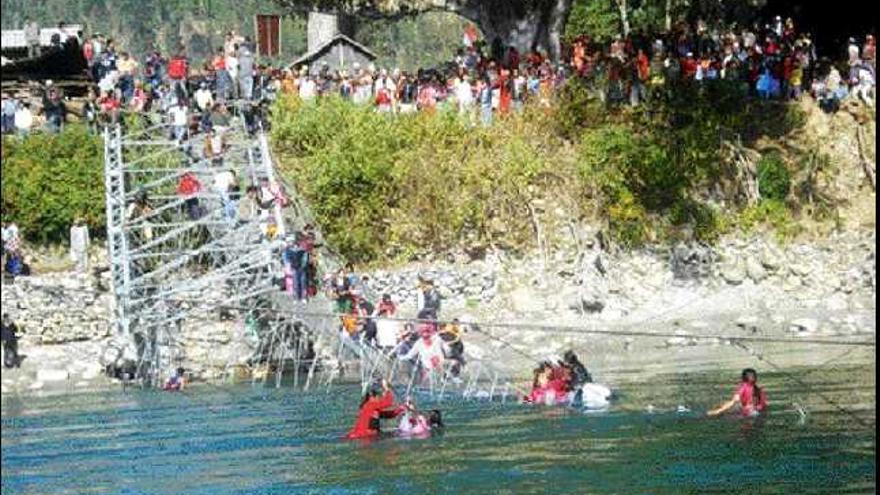 Varias personas tratan de salir del agua del río Bheri tras el derrumbe del puente colgante. / EFE