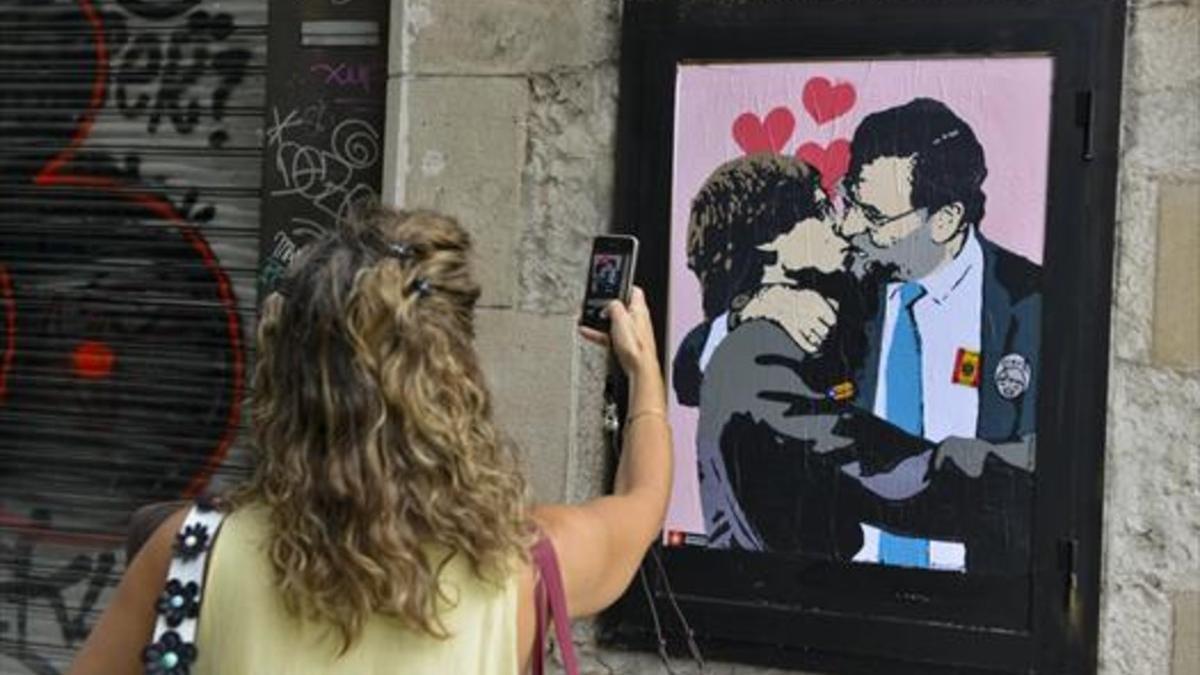 08.30 H Una mujer fotografía la obra de Tvboy en la calle del Bisbe.