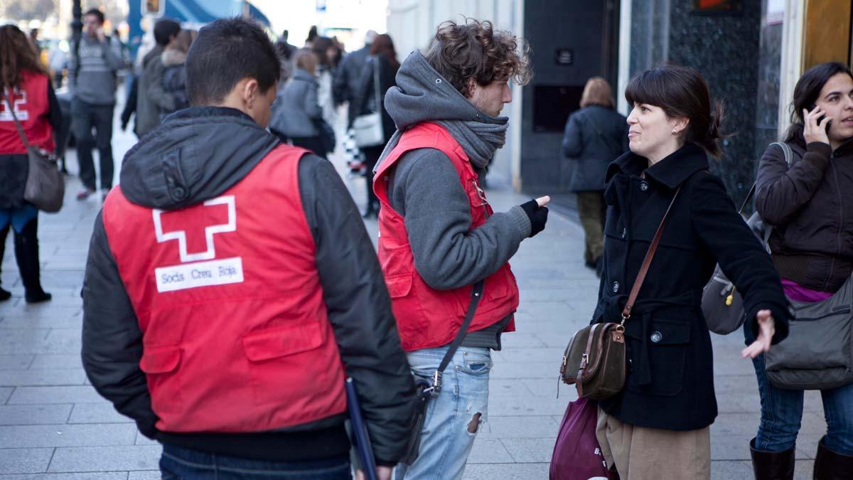 Voluntarios de la Cruz Roja intentan captar socios en la calle, en plaza de Catalunya, en Barcelona