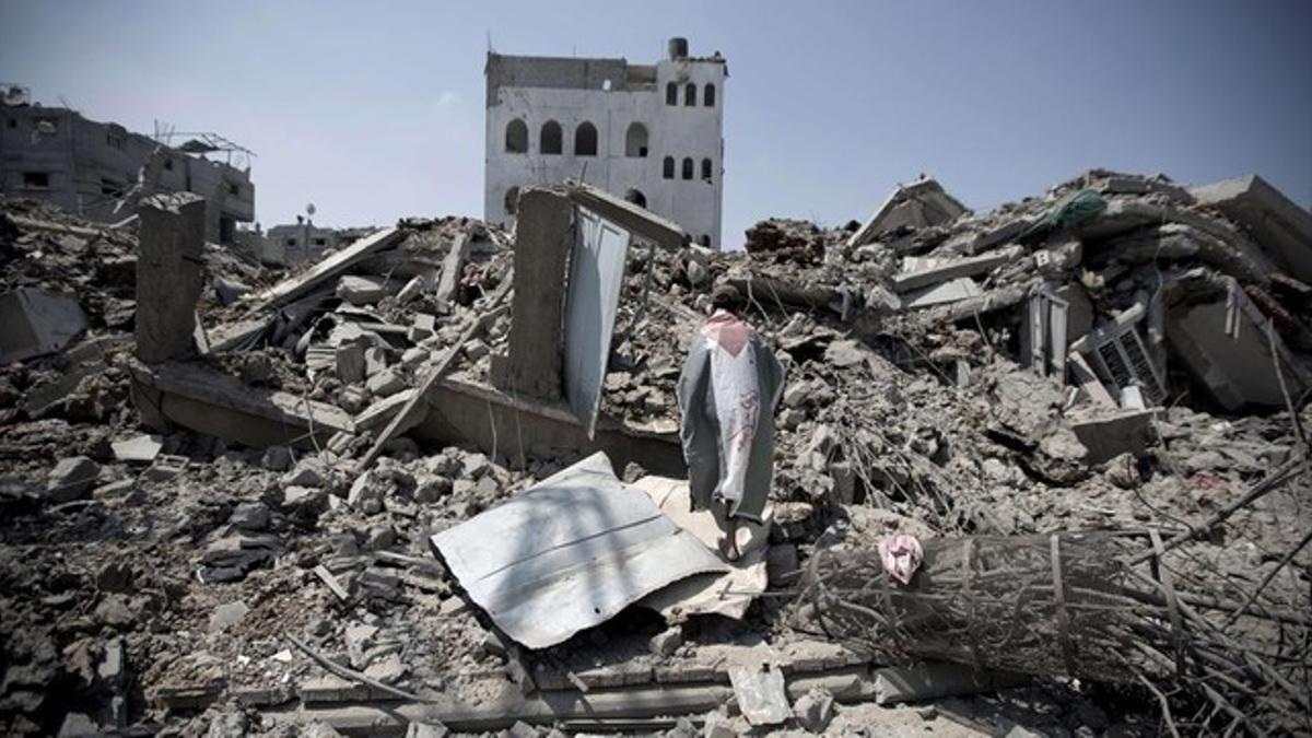 Un hombre con la bandera palestina camina por los escombros de edificios destruidos en el barrio de Shayahía, en la ciudad de Gaza, este lunes.