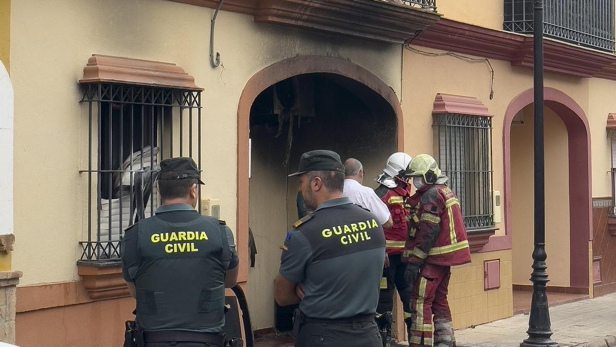 Bomberos y agentes de la Guardia Civil junto a la vivienda incendiada en Guillena.