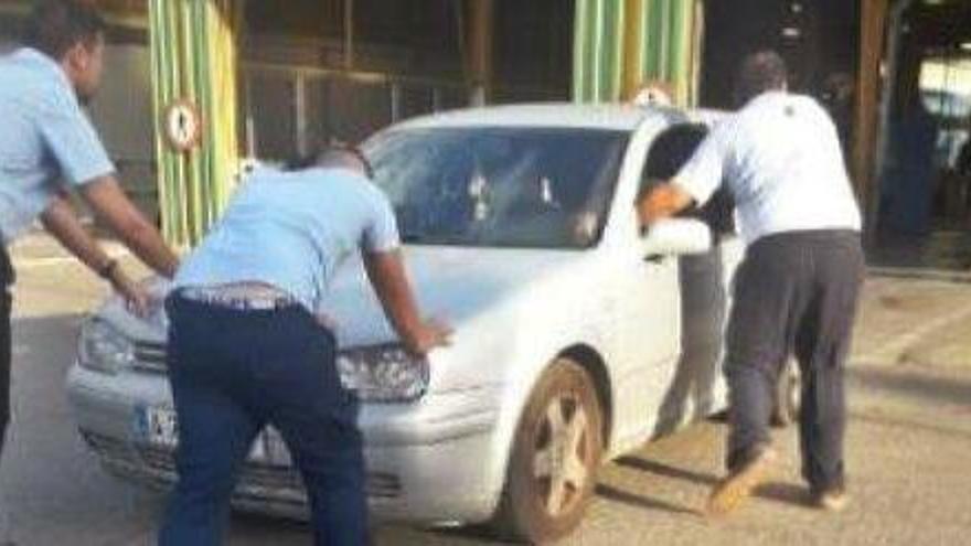 Unos operarios de la ITV empujan el coche de la afectada después del accidente en la inspección.