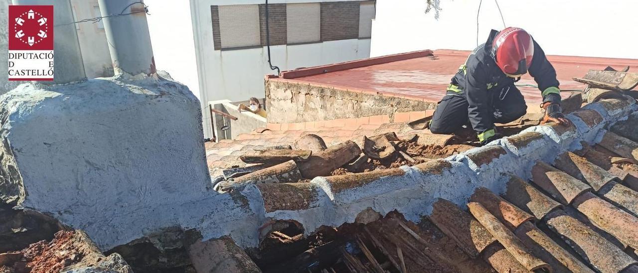 Uno de los bomberos del parque del Baix Maestrat sobre la cubierta de la vivienda afectada por el incendio.