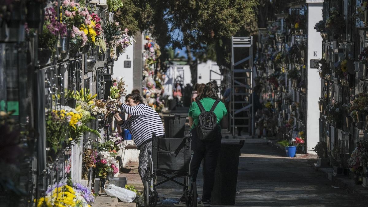 Una mujer arregla un ramo de flores en una tumba.
