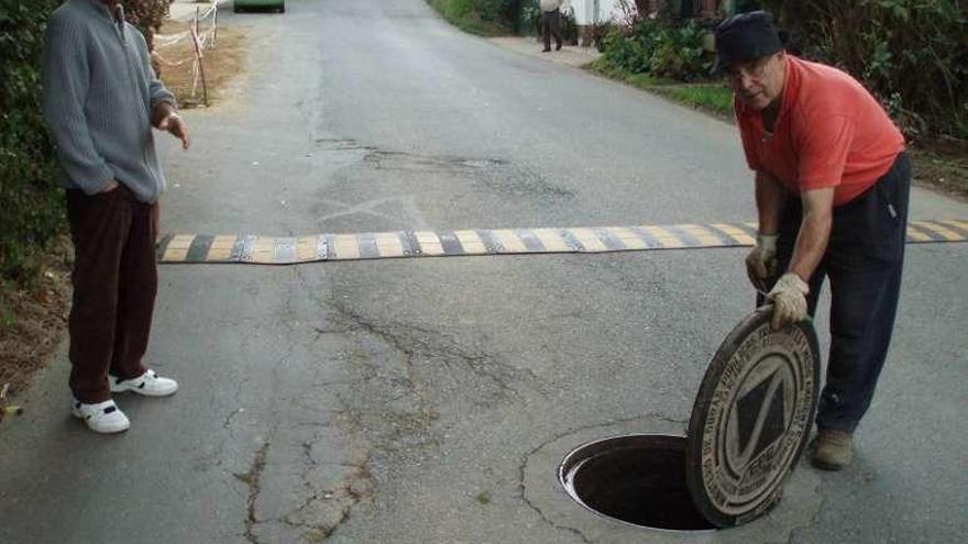 Vecinos de Nós levantan una alcantarilla en un tramo afectado.