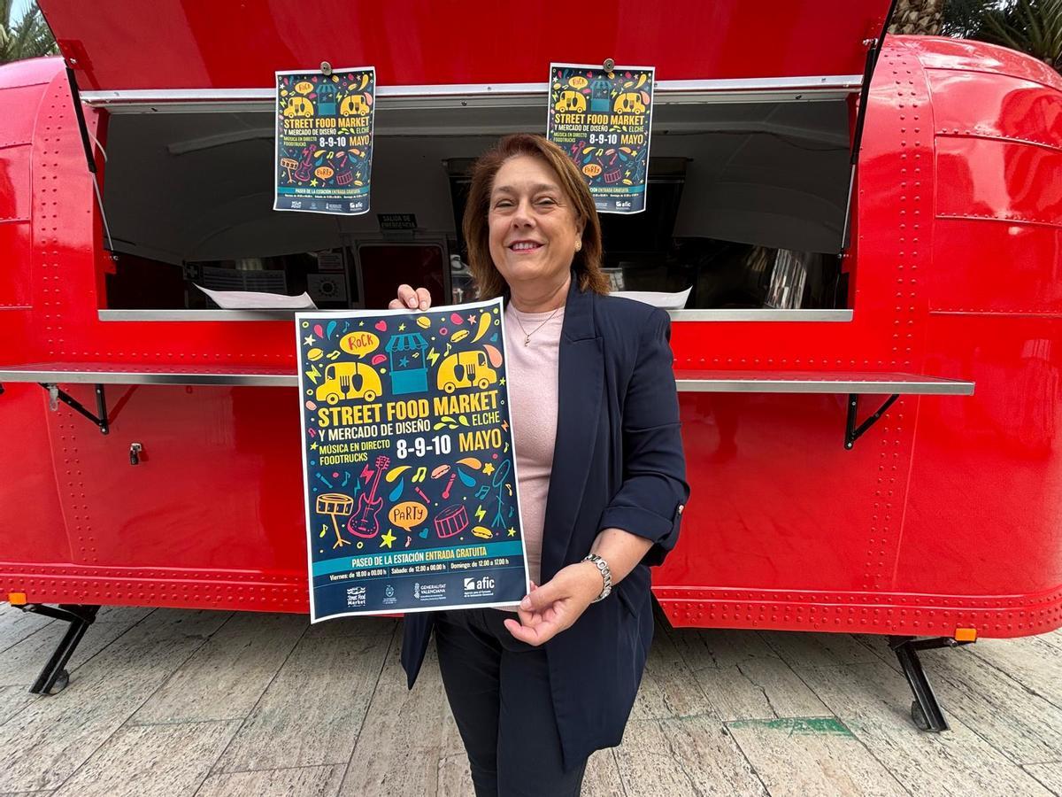 La concejala de Comercio del Ayuntamiento de Elche muestra el cartel del Street Food Market del fin de semana del 8 al 10 de mayo