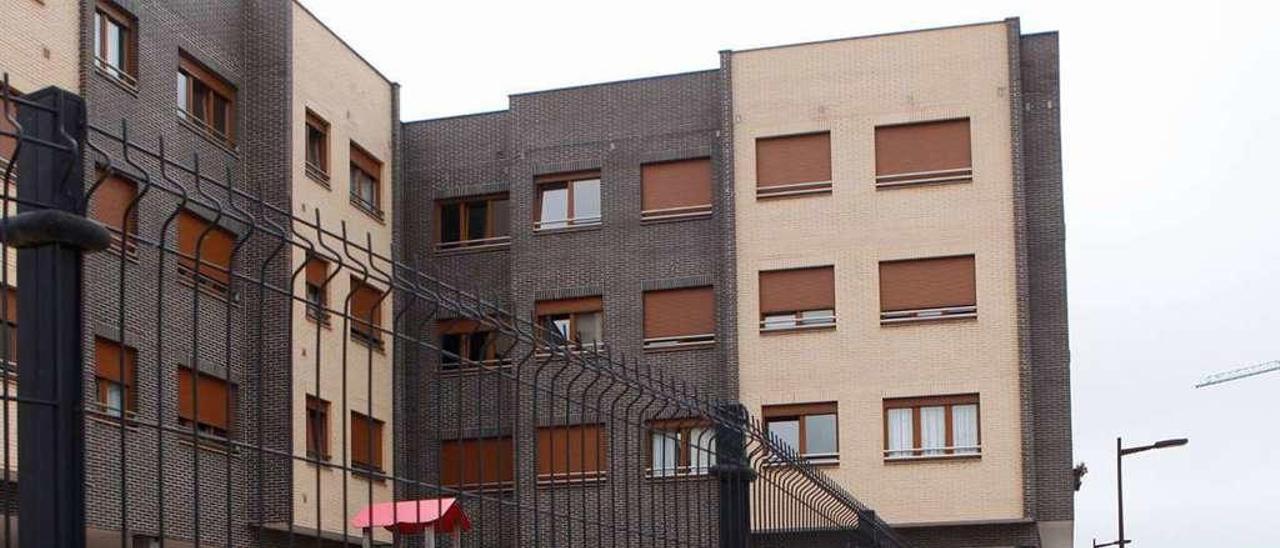 Un edificio de nueva construcción, con un parque infantil cercado con una valla, en el barrio de Nuevo Gijón.