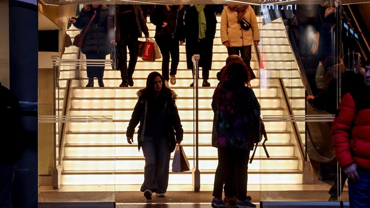 Varias personas entran y salen de un establecimiento comercial.